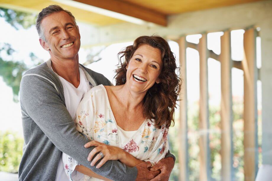 older smiling couple hugging on porch