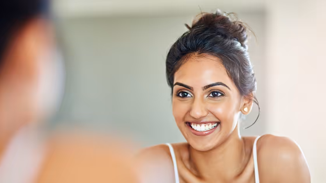 Facial aesthetics patient smiles in mirror