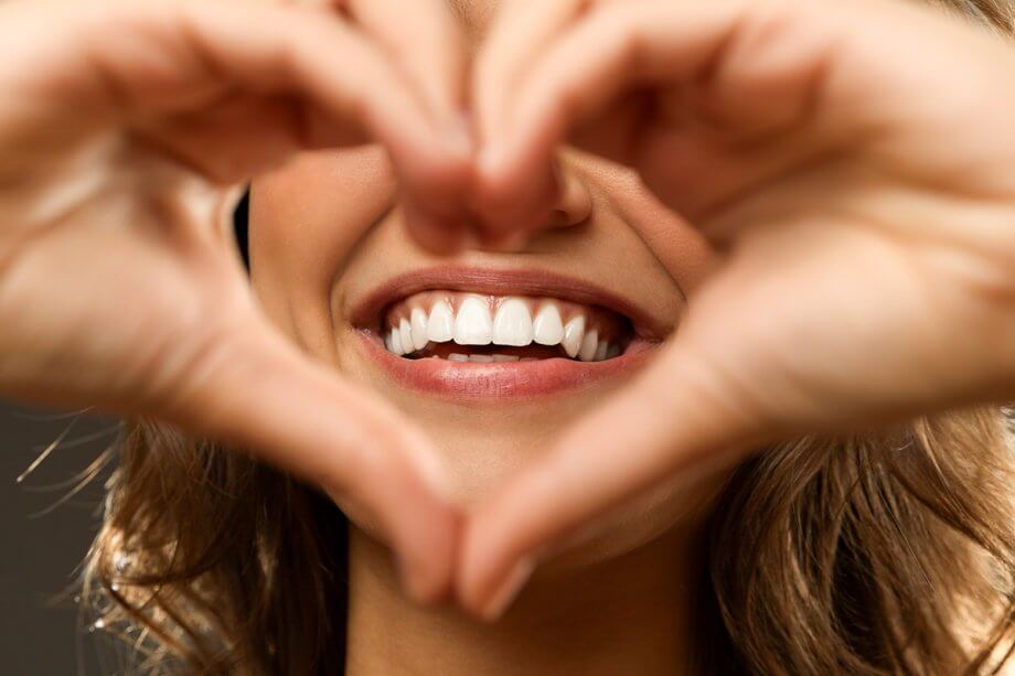 woman making heart shape with hands around smile