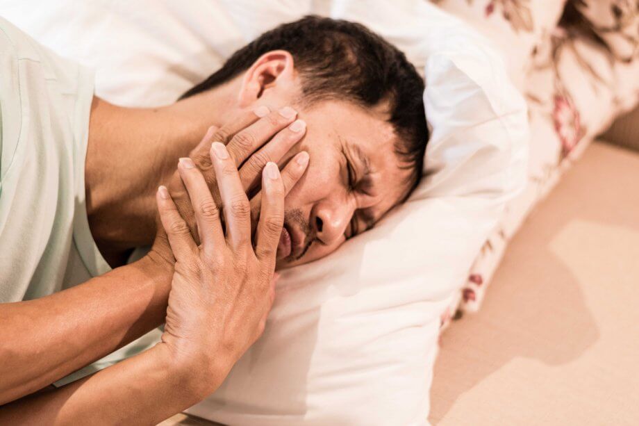 Man Lying in Bed with TMJ Symptoms