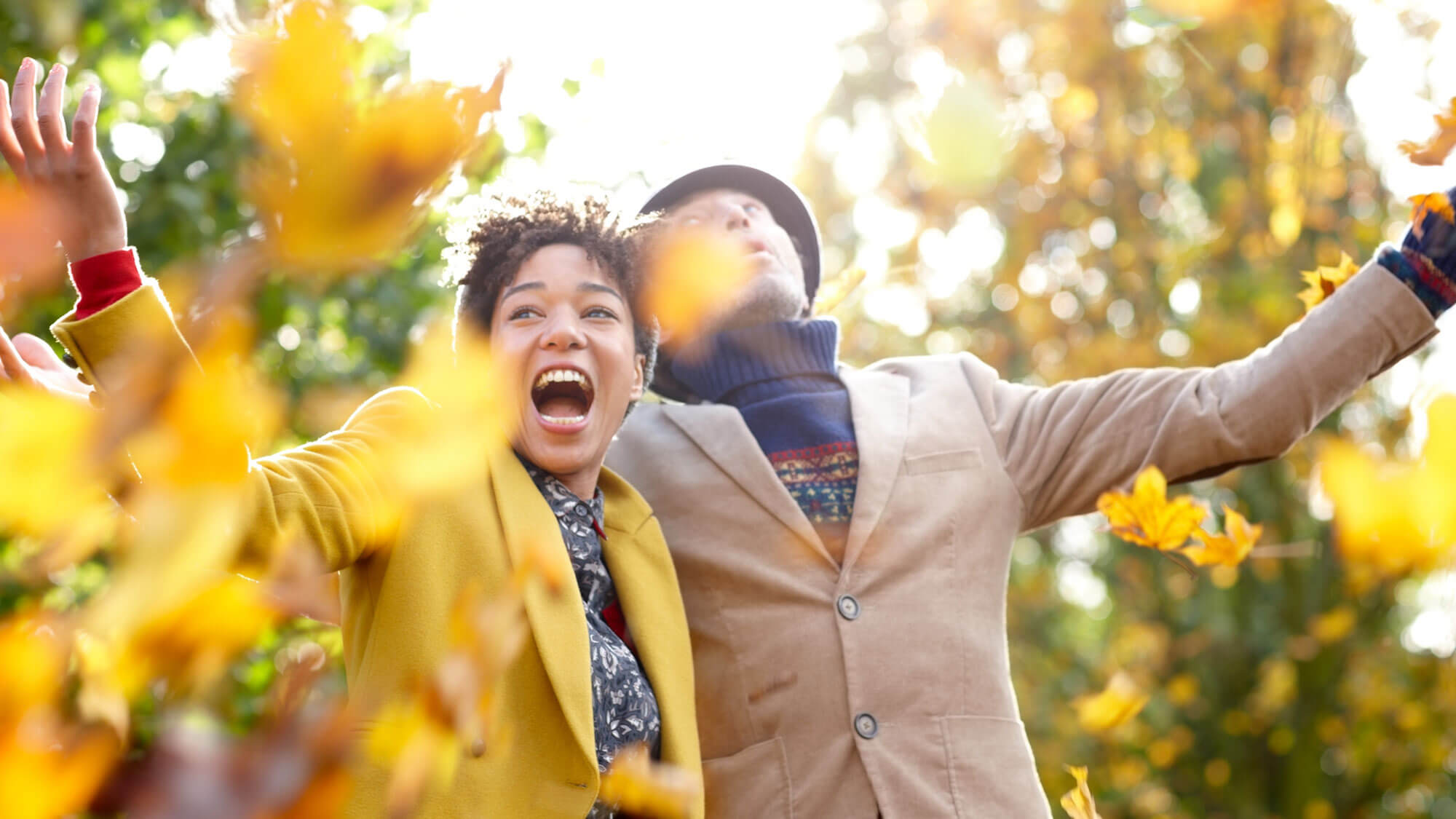 a couple outside in the fall having fun throwing leaves in the air