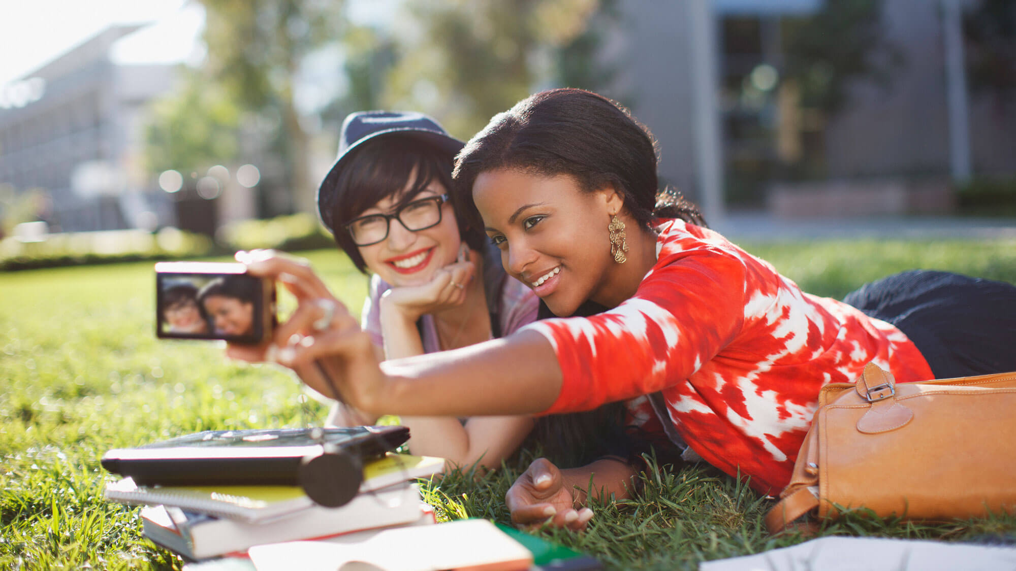 two young girls outside on the grass taking a selfie